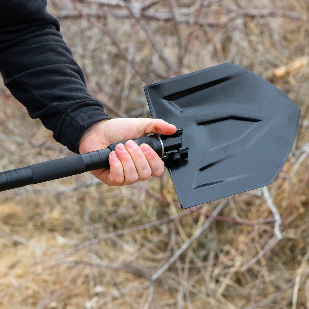 Hand holding a black folding shovel