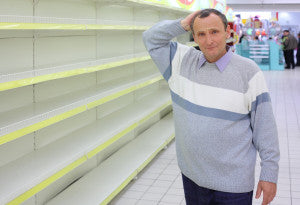 elderly man at empty shelves in  shop scratches in  nape