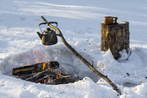 Camp fire in winter in snow wilderness cooking