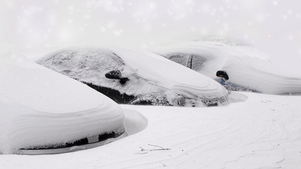 Three cars covered in ice and buried in deep snow.