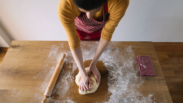 Woman kneading dough on a wooden counter.