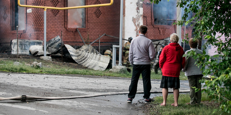 elderly family member looking at destroyed building with family
