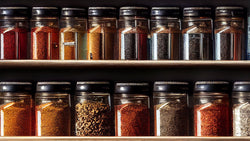 Rows of jars filled with spices in a kitchen cuboard.