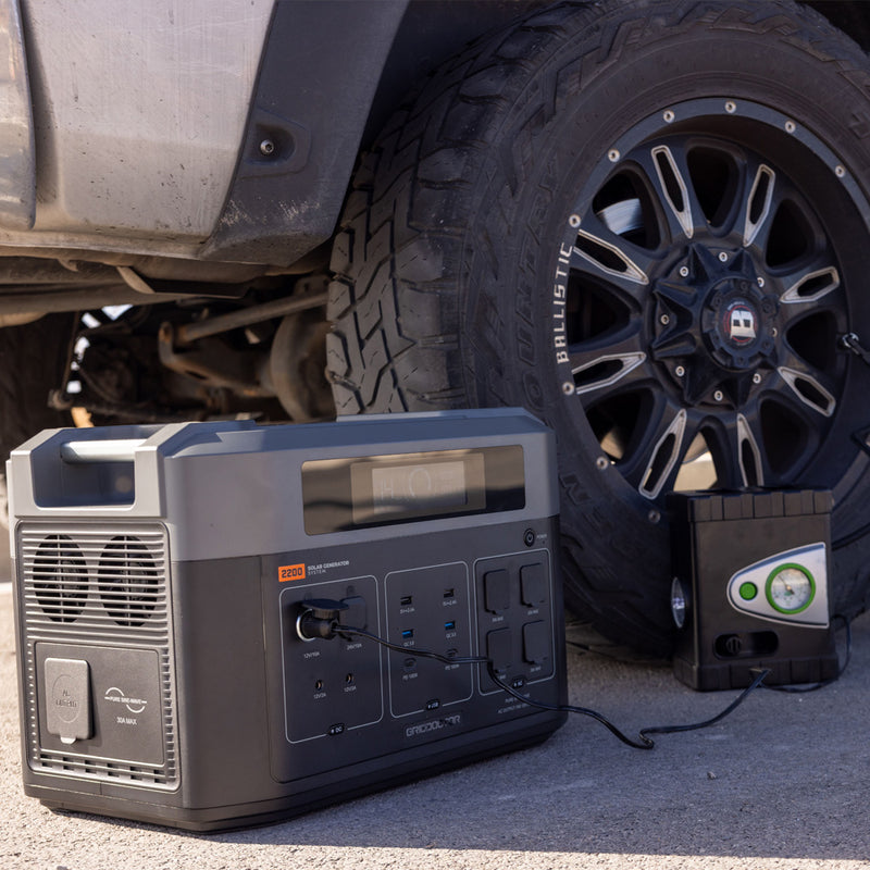 2200 Solar Power Battery by Grid Doctor positioned under a car, providing power to an electronic device for automotive repairs. (7404114083980)