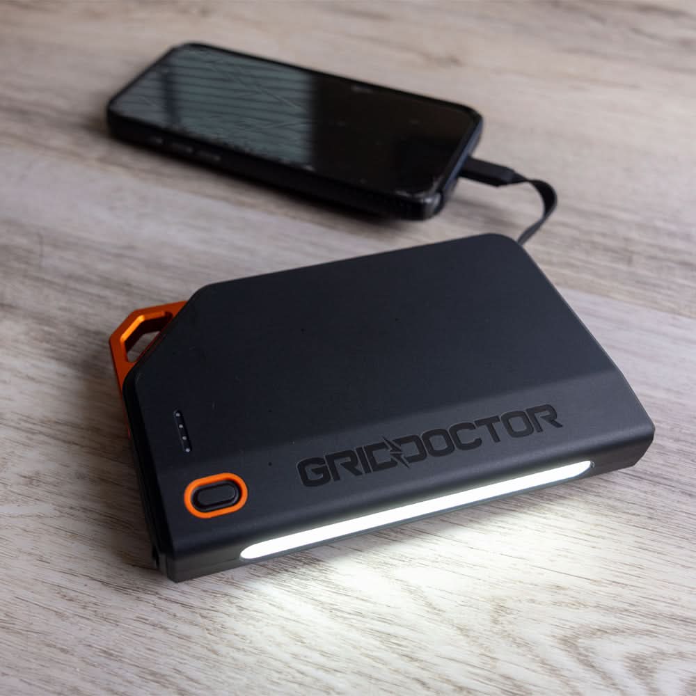 Grid Doctor 65W Power Bank charging a smartphone with the built-in LED light on