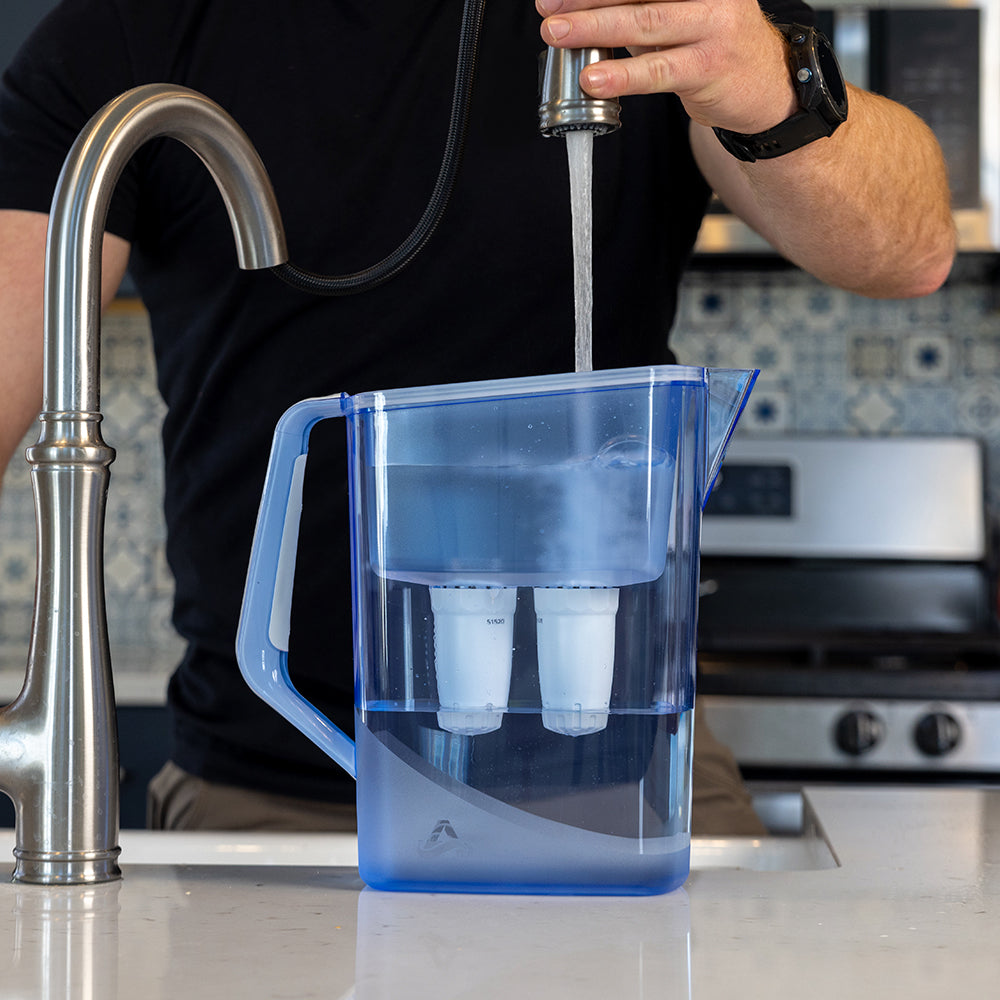 A man filles the Alexapure Pitcher from a kitchen sink.