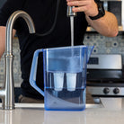 A man filles the Alexapure Pitcher from a kitchen sink.