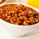 Steaming Hot Barbecue Baked Beans in a White Ceramic Bowl with a Golden Background