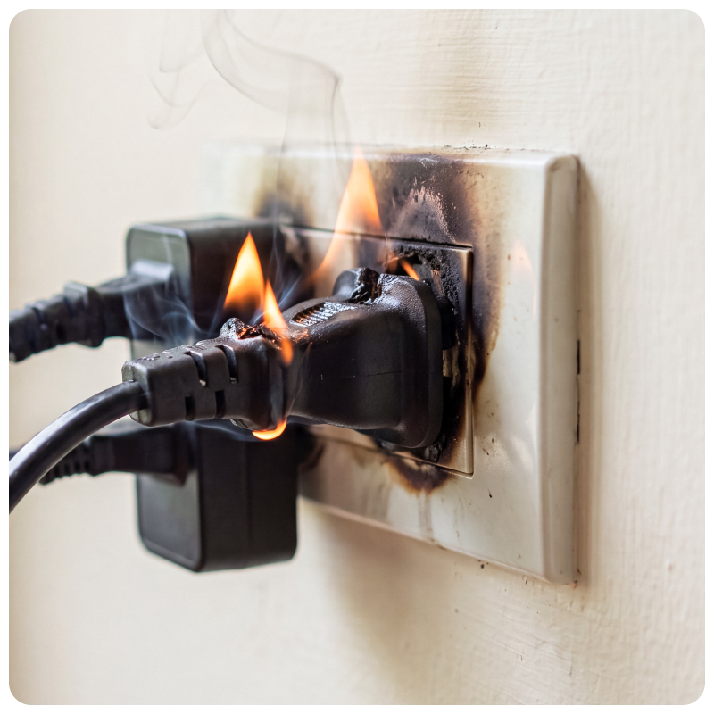 A black cord plugged into the wall, on fire