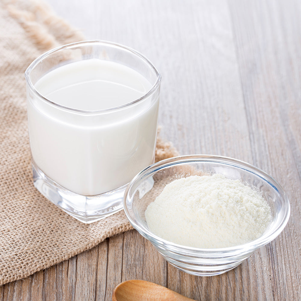Emergency Essentials Nonfat Dry Milk powder shown with prepared milk and a measuring scoop