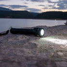 Flashlight on a rock with a lake and mountains in the background