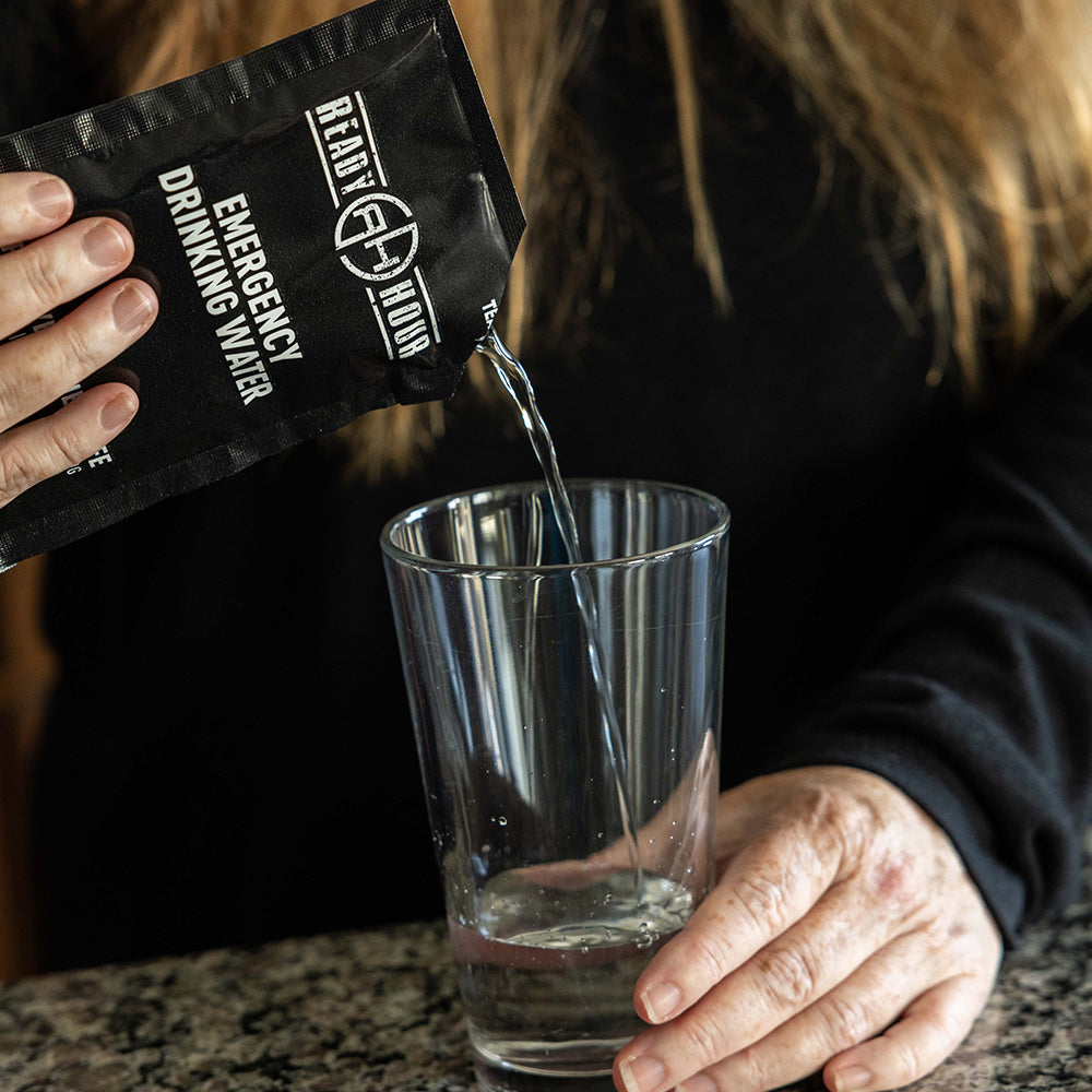 Person pouring emergency water from a black packet